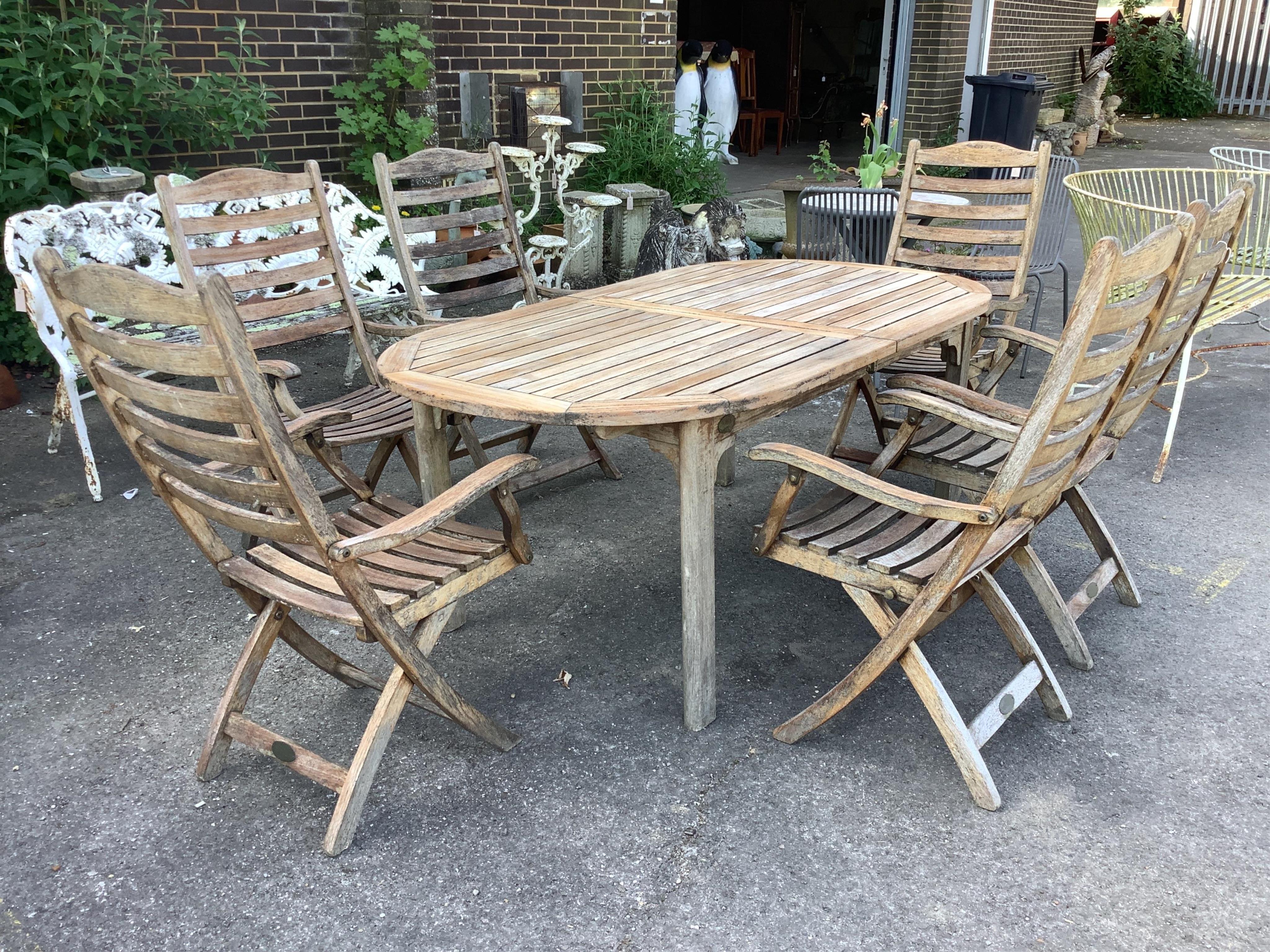 A weathered slatted teak Nova extending garden table, width 240cm extended, depth 100cm, height 71cm and six teak Alexander Rose folding chairs